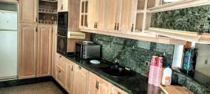 a kitchen with wooden cabinets and a sink and a microwave at Villa Hawai in Benidorm