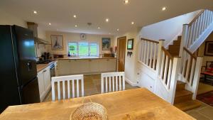 a kitchen with a table and a kitchen with stairs at Northleigh Barn in West Worlington