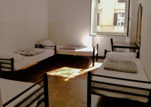 a room with three beds and a window at Minerva Rooms in Rome