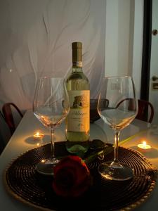 a bottle of wine and two wine glasses on a table at Urban House in Nuoro