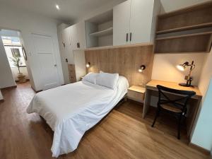 a bedroom with a white bed and a desk at Sori Apartments in Lima