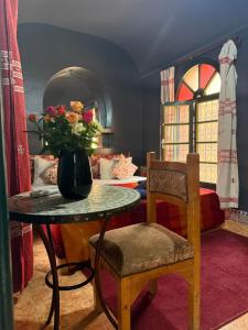 a room with a vase of flowers on a table and a chair at Casa del Sol Marrakech in Marrakesh +37 photos