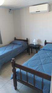 ein Schlafzimmer mit zwei Betten und einem Tisch mit Lampe in der Unterkunft Casa en Barra del Chuy-Alvorada in Barra del Chuy