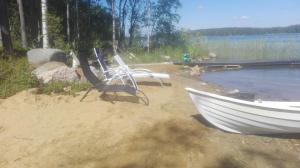 Biała łódź siedząca na piasku obok wody w obiekcie Villa Paradise at Puruvesi Saimaa w mieście Punkaharju