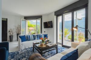 Vista Lario by Rent All Como في Carate Urio: غرفة معيشة ذات أثاث ونوافذ زرقاء وبيضاء