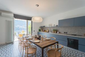 Vista Lario by Rent All Como في Carate Urio: مطبخ مع طاولة وكراسي خشبية في مطبخ