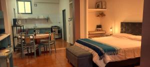 a bedroom with a bed and a table and a kitchen at "Clodin" Monoambiente Ideal, Planta Baja y Garage in La Cieneguita