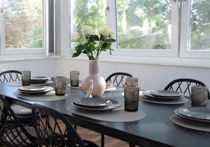 ein schwarzer Tisch mit Tellern und einer Vase mit weißen Rosen in der Unterkunft CASA LUXE - 110qm - Stadtmitte - Familienfreundlich - Parkplatz - 5km zum Legoland in Günzburg