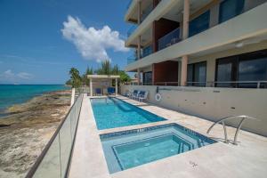 a house with a swimming pool next to the ocean at Sea Dreams 3-contemporary Condo Wpanoramic Views in West Bay
