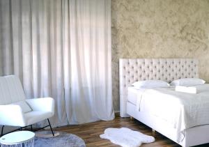 ein Schlafzimmer mit einem weißen Bett und einem Stuhl in der Unterkunft CASA LUXE - 110qm - Stadtmitte - Familienfreundlich - Parkplatz - 5km zum Legoland in Günzburg