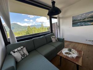 a living room with a green couch and a large window at Steinbock Apartement in Bad Goisern