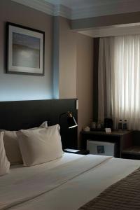 a hotel room with a bed and a window at Santa Inn Hotel in Balneário Camboriú