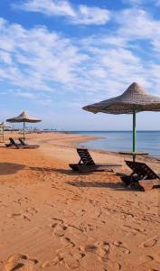 two beach chairs and umbrellas on a beach at قرية لاجولى السخنه للعائلات فقط in Ain Sokhna