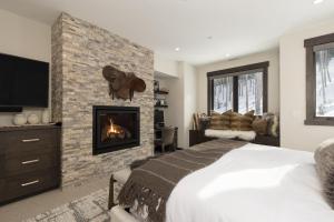 a bedroom with a fireplace and a bed and a tv at Spanish Peaks | Highlands Cabin 36 in Big Sky