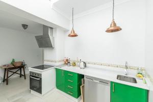 una cocina con armarios verdes y blancos y fregadero en Casa Nana Townhouse with seaview, en Torrox