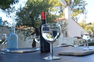 a bottle of wine sitting on a table with wine glasses at L'olivier 5min de la plage -Touristes et Ouvriers- in La Barre-de-Monts