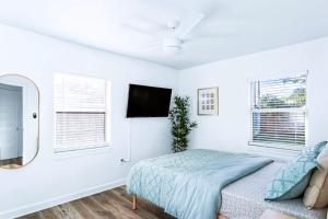 a white bedroom with a bed and a tv at Pelican's Perch in Downtown EGAD in Melbourne