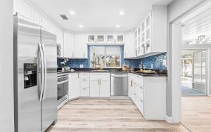 a kitchen with white cabinets and a stainless steel refrigerator at Pelican's Perch in Downtown EGAD in Melbourne