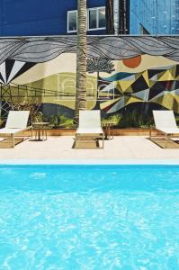 two shots of a pool with chairs and a mural at Santa Inn Hotel in Balneário Camboriú