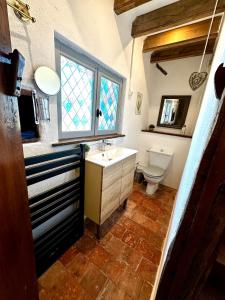 a bathroom with a sink and a toilet and a window at Charme ancien pigeonnier au cœur de la campagne in Ourouer-lès-Bourdelins