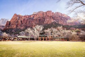 a building in a field with a mountain in the background at Zion Lodge - Inside the Park in Springdale