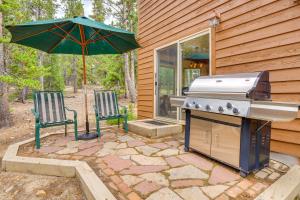 a grill and two chairs and an umbrella on a patio at Hot Tub and Game Room Fairplay Cabin Near Hiking in Fairplay