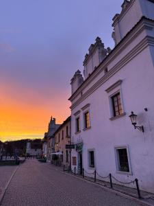 a building on a street with a sunset in the background at Kamienica Biała in Kazimierz Dolny