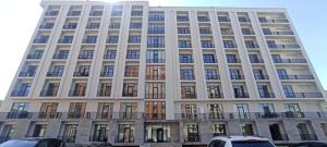 a tall white building with windows and cars parked in front at New Alvina 44 in Tsaghkadzor