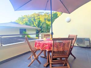 a table and two chairs with an umbrella on a balcony at Kaimana Blue Pearl - Wifi - Pool - AC in Mahina