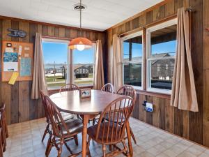 Un comedor con mesa y sillas y ventanas. en 4085 - Ten Forward, en Kitty Hawk