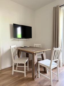 mesa de madera con 2 sillas y TV en la pared en Appartement bis 3 Personen gehobene Ausstattung, en Bad Münder am Deister