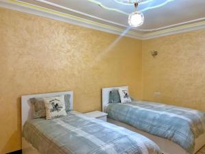 a bedroom with two beds and a chandelier at Grand Appartement Luxueux En Plein Taroudant in Taroudant