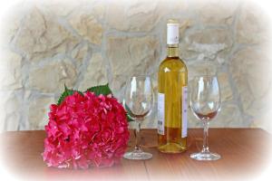 a bottle of wine and two wine glasses and a flower at Apartments Riva Povljana in Povljana