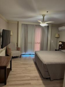 a bedroom with a bed and a couch and a chair at Flat 305 - Gramado in Gramado
