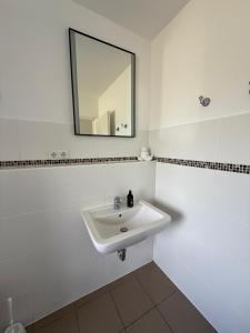 Un baño blanco con lavabo y espejo. en Appartement bis 3 Personen gehobene Ausstattung, en Bad Münder am Deister 4 fotos más