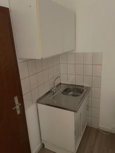 a small kitchen with a sink and white cabinets at Hotelshausbückeburg in Bückeburg