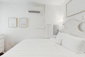 a white bedroom with a white bed and two pictures on the wall at Bowen Village 2118B in Charleston +35 photos