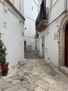 an empty alley with white buildings and a potted plant at Casa Giulia in Martina Franca
