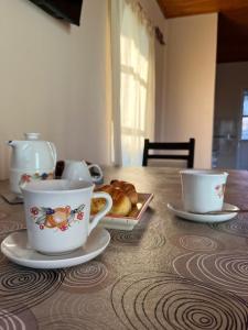 a table with two cups and a plate of croissants at Casa Passiflora II in Villa Elisa +20 photos