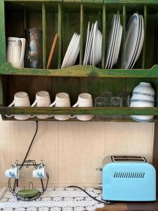 a green shelf with plates and dishes and a toaster at Casa Nova in Apúlia