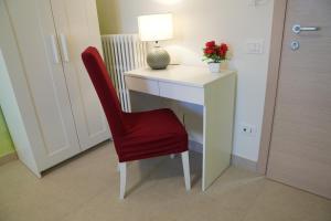una silla roja sentada junto a un escritorio con una lámpara en Green House, en Matera