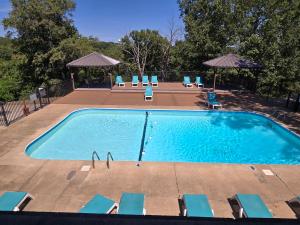 een groot zwembad met stoelen en parasols bij Swan's Woodland Getaway Condo in Reeds Spring