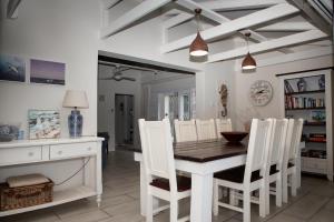 ein Esszimmer mit einem Tisch und weißen Stühlen in der Unterkunft Sea Cottage in Port Shepstone