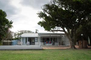 ein weißes Haus mit einem Baum im Hof in der Unterkunft Sea Cottage in Port Shepstone