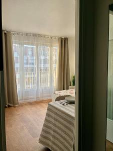 a room with a window with curtains and a table at Studio lumineux, 10min de Paris in Issy-les-Moulineaux