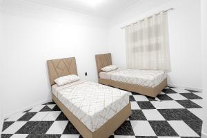 two beds in a room with a checkered floor at Ftouh House 2 Heart of Tangier in Tangier