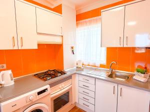 a kitchen with white cabinets and an orange wall at Piso los Agaves in Costa de Adeje