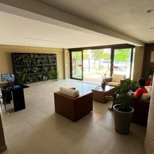 a large living room with couches and plants in a building at Capri Residence Luxo 02 quartos by Premium Reservas in Porto De Galinhas