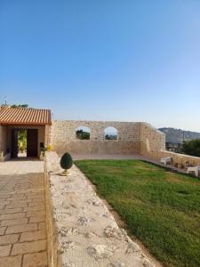 a building with a stone wall and a yard at Masseria Torre Saracena in Agrigento