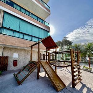 two wooden play structures in front of a building at Capri Residence Luxo 02 quartos by Premium Reservas in Porto De Galinhas